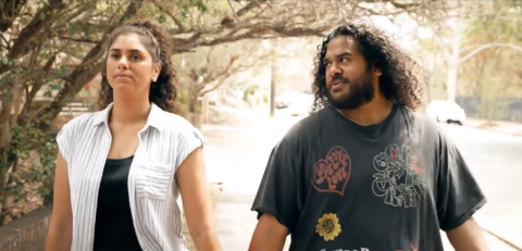 Two young people walking while holding hands outside