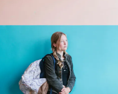 Young girl leaning against blue wall. 